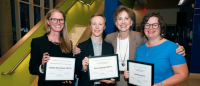 Four individuals holding award certificates